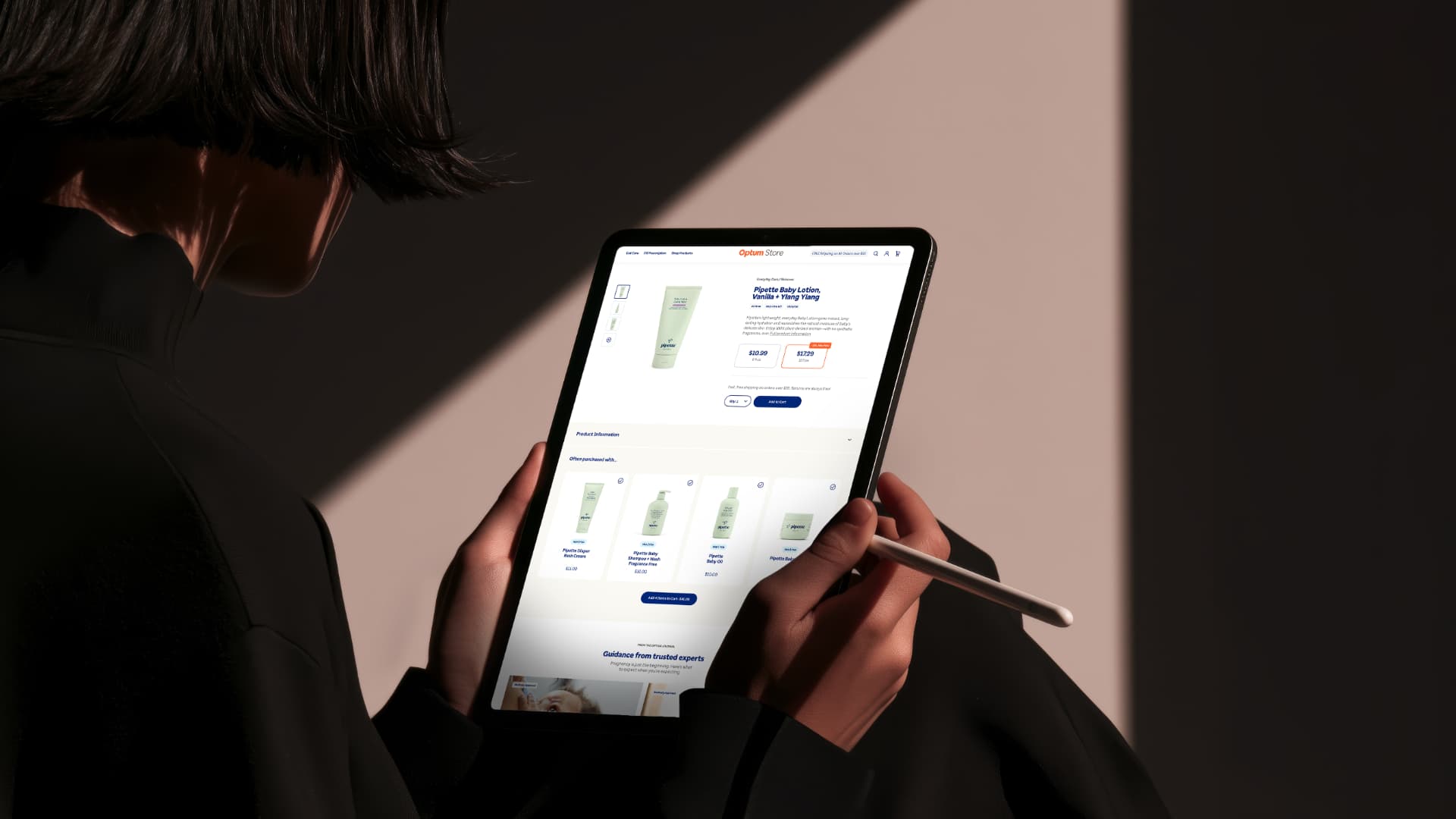 A person holding a tablet displaying the redesigned Optum Store product detail page.