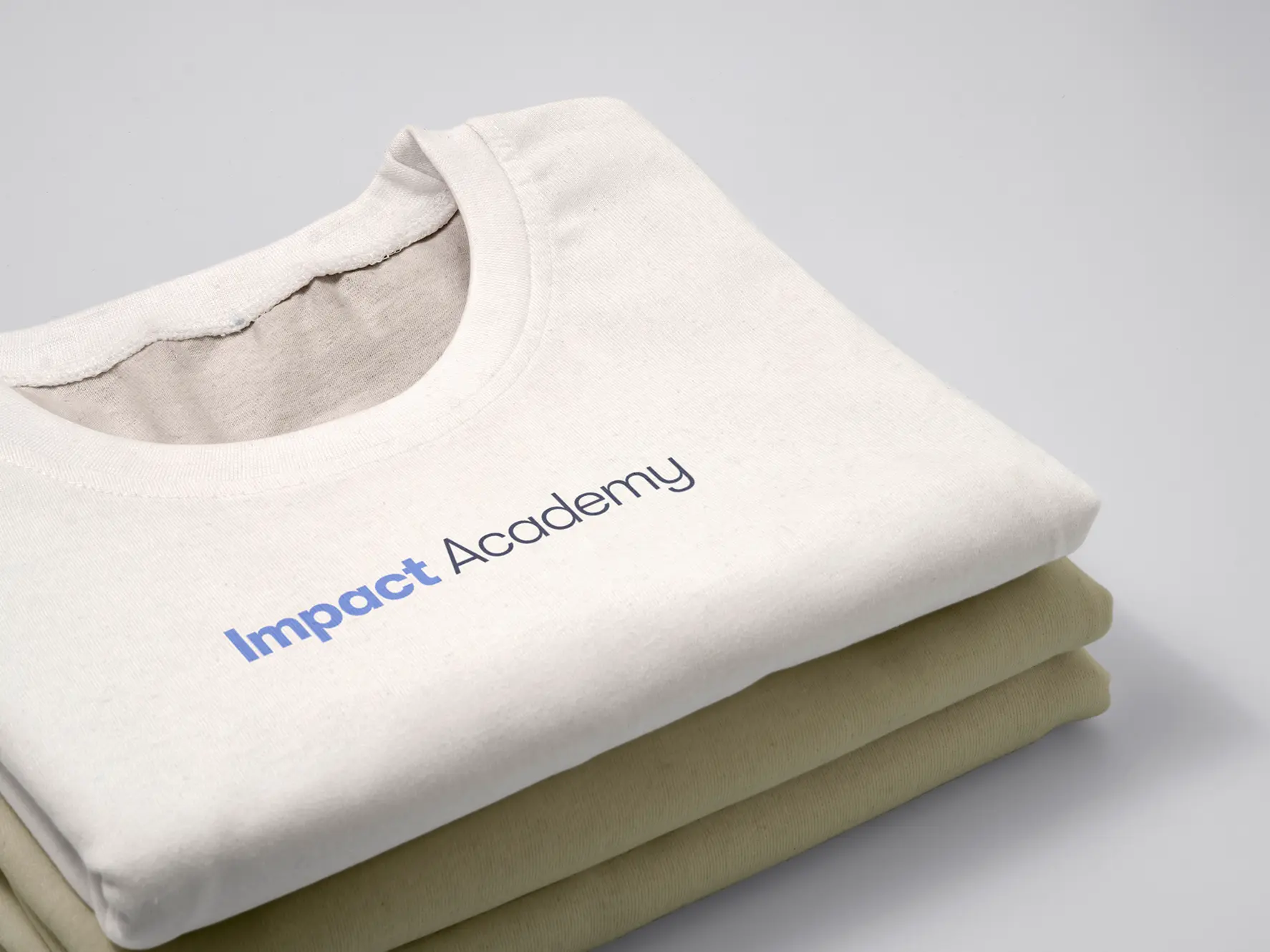 Folded Impact Academy t-shirts with the logotype printed across the chest.